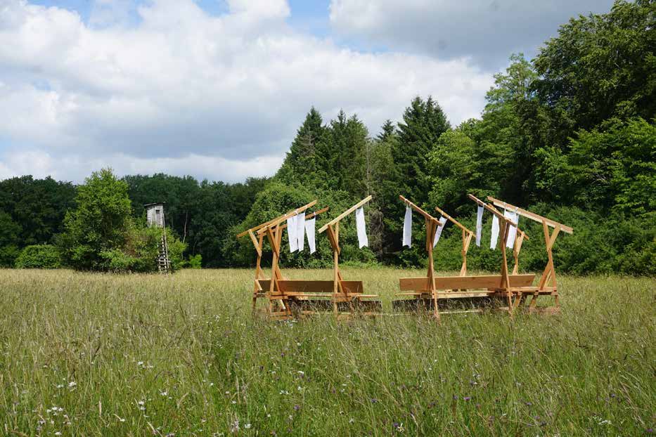 A timber structure and suspended fabric in a meadow in the Schwalb valley